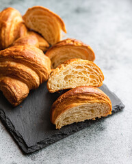Cut in half croissant with inside texture and thin crisp layers on stone board, grey background. Delicious french pastry.