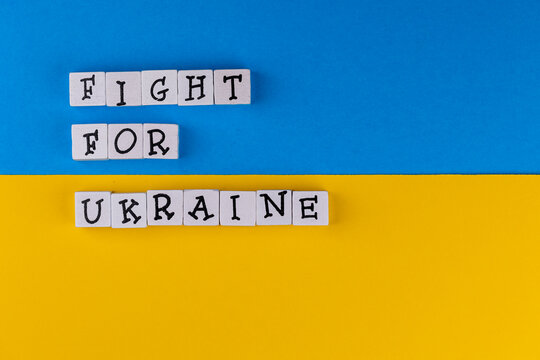 The sentence "Fight for Ukraine" composed of letters on the background of Ukrainian flag. Photo taken under artificial, soft light