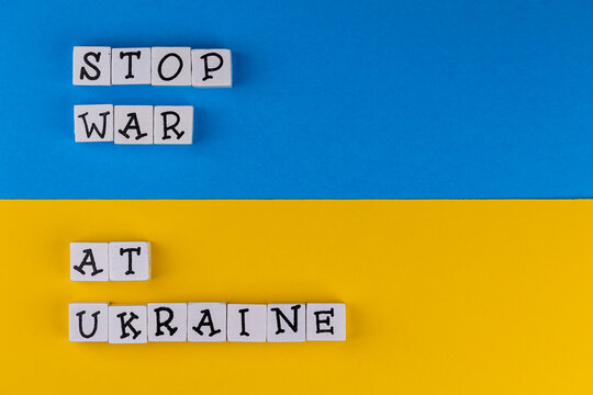 The sentence "Stop war at Ukraine" composed of letters on the background of Ukrainian flag. Photo taken under artificial, soft light