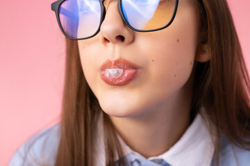 Cropped photo of funny school girl in glasses makes bubble gum wearing school uniform on pink background, school fun concept.