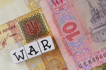 The sentence "war" composed of letters on the background of Ukrainian banknotes. Photo taken under artificial, soft light