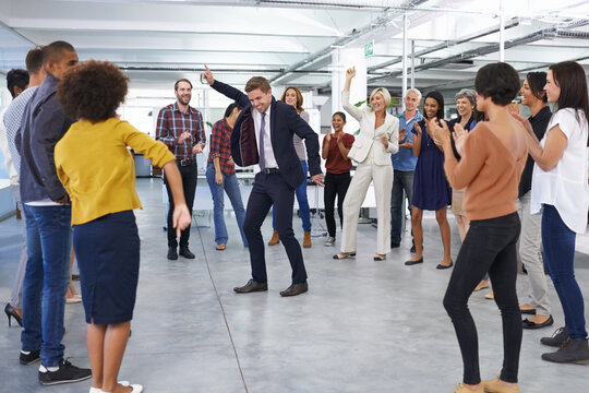 All Work And No Play.... Shot Of A Businessman In A Suit Dancing In The Office To Cheers From Coworkers.