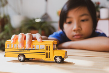 Asian child girls lonely play the yellow toy school bus during their break from school or at home. , Concept Learn at home to stop the transmission of the coronavirus or covid-19