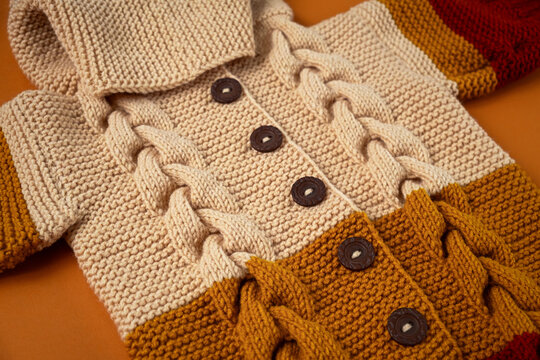 Knitted clothes color background. Handmade children's clothing. Knitted suit close-up view from above. The concept of hobby, individual marketing, entrepreneurship. Autumn time is cozy and warm.