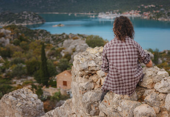 Fototapeta na wymiar Travel and tourist attractions at Kekova island, Turkey. Man traveler explores ruins castle of Simena with view of sea bay and Kekova Island with famous flooded city. Tourist attractions in Turkey.