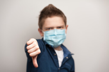 european boy with medical mask on face shows dislike