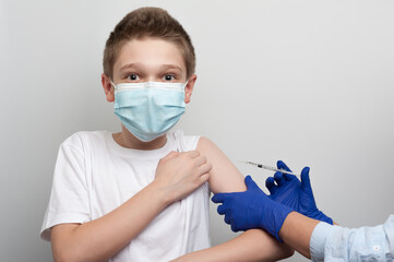 Medical and vaccination topic. Hands of nurse with syringe making vaccine injection to caucasian boy