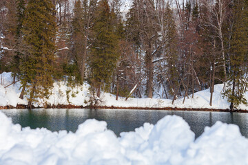 Winter landscape of the lake. river. A beautiful pond with tall Christmas trees. The green sea. Park. The ground is covered with snow. For postcards.