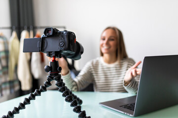 Naklejka premium Female vlogger sitting beside desk with laptop, record herself