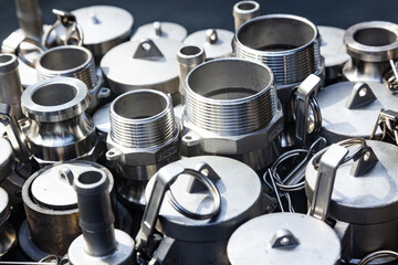 New bushings, couplings, threaded connections and nipples made of stainless steel. A pile of steel fittings close-up.