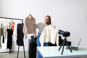 Fashion blogger woman in jeans and turtleneck showing casual colorful shirts on camera. .