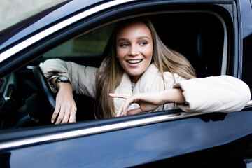 Happy beautiful woman is driving a car.