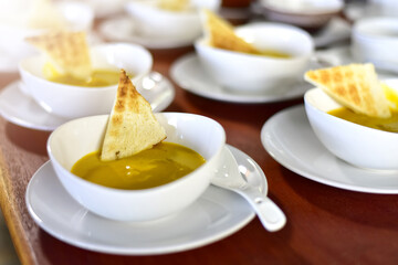 top view of Pumpkin cream soup in a white cup with toast on rustic wooden table. selected focus