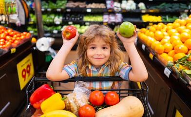 Child boy is shopping in a supermarket. Child choosing a apple in a store. Little boy choosing...
