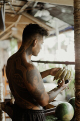 Young handsome man body in tattoos chooses fruits in the store, bananas.