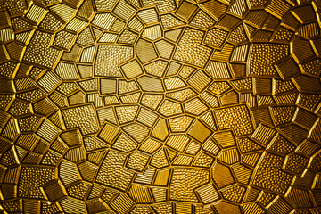 Golden antique background with polygonal texture. Gold plate with a geometric pattern, close-up.