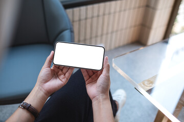 Mockup image of a woman holding and using mobile phone with blank desktop screen