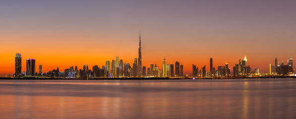 Panorama of Dubai Business Bay skyline at night after sunset with colorful illuminated buildings...