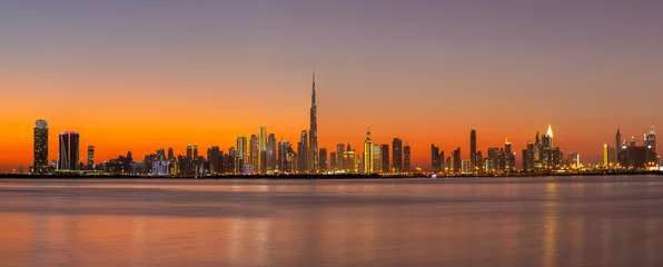 Crédence de cuisine en verre imprimé Dubai Panorama of Dubai Business Bay skyline at night after sunset with colorful illuminated buildings and calm Dubai Creek water.