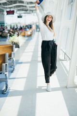 Cheerful businesswoman waiting for her flight at airport. Young woman at the airport. Travel. A young woman is waiting her flight in waiting hall in airport.
