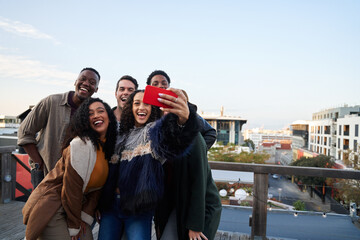 Multi-cultural group of friends taking a selfie at a rooftop party. Attractive young adult friends,...