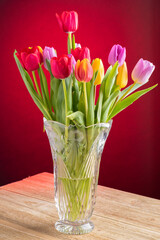 a big bouquet of tulips of various colours in crystal vase