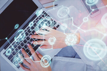 Double exposure of woman hands working on computer and social network theme hologram drawing. Top...