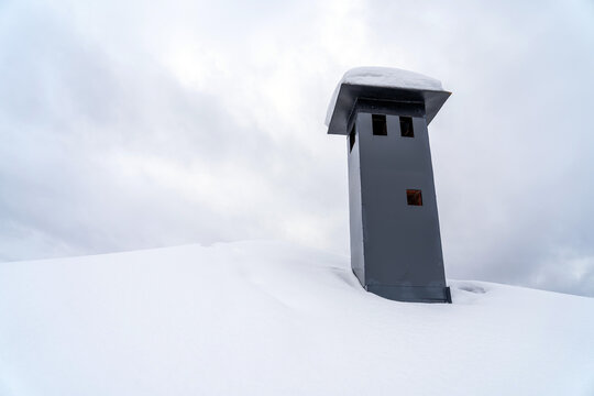 Close-up View Of Brick Stone Pipe Covered With Metal Sheets And Black Smoke Box On Snowy Roof At Winter