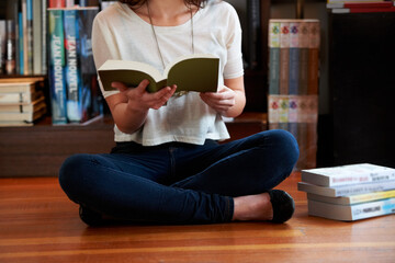 Reading a few passages.... A cropped shot of a young woman sitting on the floor of a bookshop and...
