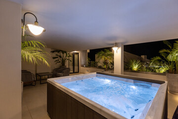 Illuminated hydromassage bathtub on the hotel terrace in the evening
