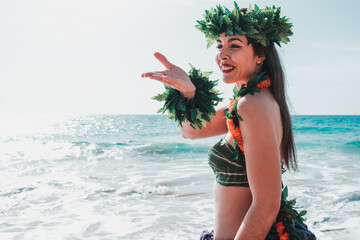 Woman blows a kiss with her hand.  Miss hula poses on the beach waving goodbye. Gorgeous woman dressed in traditional Hawaiian dance attire enjoying views of a spectacular paradise beach