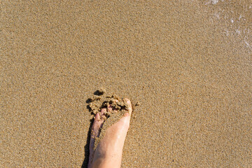 Foot half buried under the sand of the beach shore