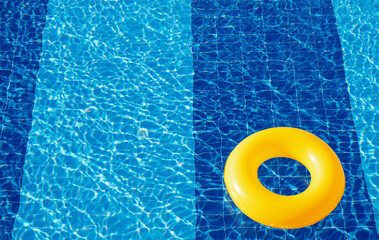 Yellow pool float, ring floating in a refreshing blue swimming pool