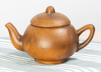 ceramic brown teapot stands on a white background of the table