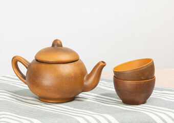 ceramic brown teapot with cups stands on a white table background