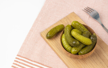 Crispy pickled gherkins in a ceramic bowl with a fork on the table