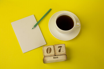 coffee with a notebook and the date of March 7 on a yellow background