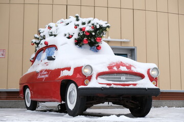 Almaty, Kazakhstan - 12.21.2020 : A red car with a decorated Christmas tree stands in the center of the city. Street design.