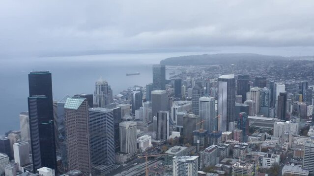 Drone shot pulling away from Seattle's downtown sector on a cloudy day.