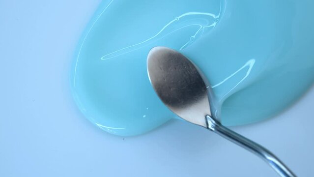The texture of a blue cream or gel close-up. A metal spatula smears a blue substance on the surface. An advertising concept for face and body care cosmetics. Health care products.