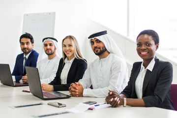 Multiethnic western and middle eastern business team working together in an office of Dubai. Sales people and employees at work on new projects