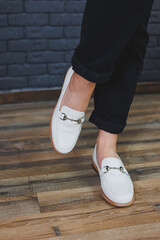Close-up female legs in black trousers and leather beige moccasins. New spring-summer collection of...
