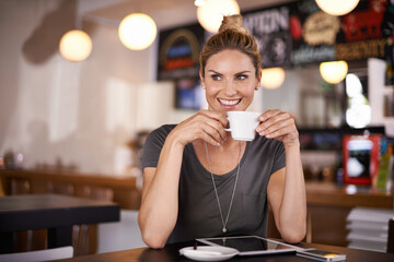 This coffee is making my day. A beautiful young woman drinking coffee at a coffee shop.