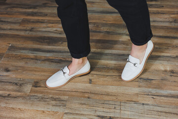 Close-up female legs in black trousers and leather beige moccasins. New spring-summer collection of...