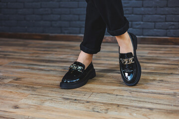 Close-up female legs in black trousers and leather black shoes. Women's shoes in patent leather...