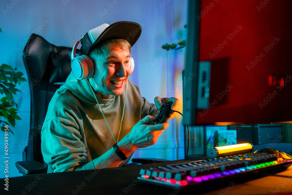 Wall mural Pro Gamer Man playing computer games. Player using controller for virtual tournament gaming space shooter at home