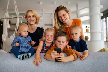 Portrait of happy big family. Gay couple of women smiling and having fun with children at home