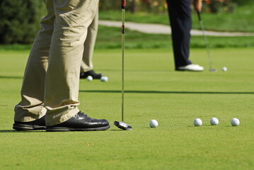 Almaty, Kazakhstan - 09.17.2008 : A golfer with a club and balls on a green field. View at the feet.