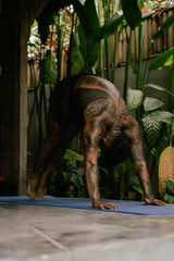Young latin american tattooed man practice yoga outdoors during retreat vacation in Bali, stretching, meditation, wellness