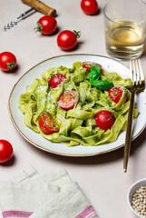 Linguini pasta with pesto sauce, tomatoes and cheese. Healthy eating. Vegetarian food. Italian cuisine.